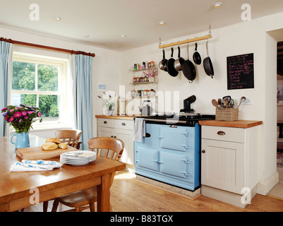 Landhausküche mit blauen Aga und Frühstück Tisch und Tafel und Pfannen hängen oben Stockfoto