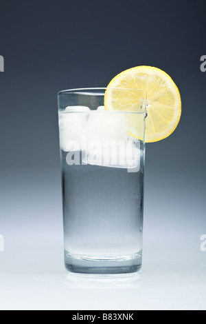 Hohes Glas Wasser mit Eiswürfeln und einem Stück Zitrone in der Nähe von Studio Stockfoto