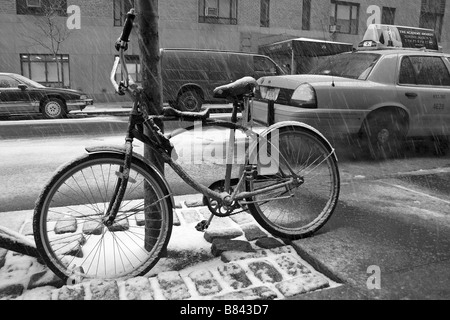 Ein Fahrrad steht im Schnee wartet ein Taxi auf der Straße, obere Westseite der Insel Manhattan, New York City, USA Stockfoto