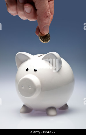 Sparschwein mit Fingern, eine Münze in Stockfoto