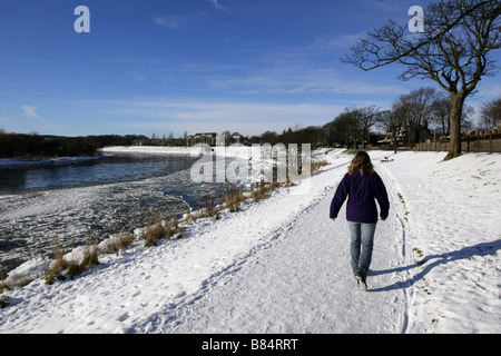 Walker auf Pfad neben gefrorenen Fluss Dee in der Stadt Aberdeen, Schottland, UK, mit riesigen Brocken aus Eis und Schnee im Winter. Stockfoto