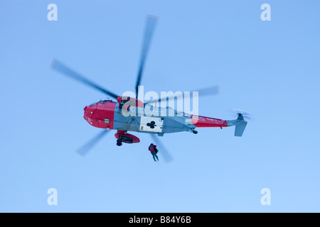Ein Navy Sea King Hubschrauber Crew und Mountain Rescue Team-Mitglieder behandeln eine schwerverletzter walker Stockfoto