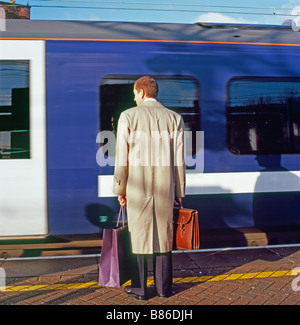 Menschen Mann Geschäftsmann wartet mit Einkaufstasche auf dem Bahnsteig in Stratford Station Bahnhöfen im East End von London England Großbritannien KATHY DEWITT Stockfoto