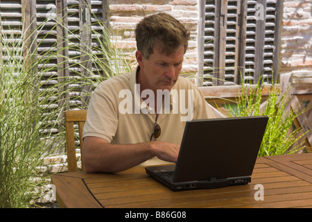 Man arbeitet an einen Laptop im Garten, Frankreich Stockfoto
