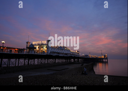 Brighton Pier in der Abenddämmerung mit Magenta Winterhimmel spiegelt sich in der ruhigen See. Bild von Jim Holden. Stockfoto