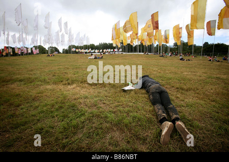 Ein Mann liegt mitten am Tag schläft in einem Feld auf dem Glastonbury Festival in PIlton, Somerset in England. Stockfoto