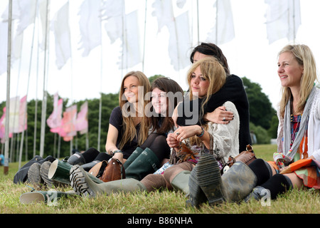 Eine Gruppe von Mädchen genießen Sie die Musik unter Flaggen auf dem Glastonbury Festival in Pilton, Somerset in England saß. Stockfoto