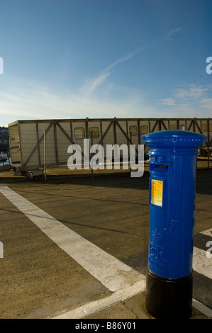 Ein Guernsey blauen Briefkasten vor dem St Peter Port Harbour Terminal mit Zufahrtsrampe hinter. Stockfoto