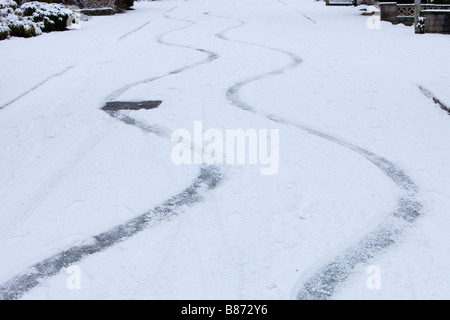 Bremsspuren in den Schnee von einem Auto auf einer steilen Straße in Ambleside UK Stockfoto