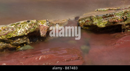 Wasser fließt sanft entlang und über kleine Felsen Stockfoto