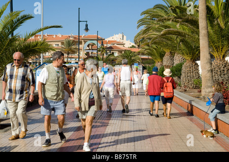 Masse der Leute schlendern die Strandpromenade direkt am Meer in Los Cristianos, Teneriffa. Stockfoto