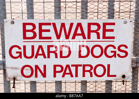 Hüten Sie sich vor Wache, die Hunde auf Patrouille am Zaun in Geschäftsräumen zu unterzeichnen Stockfoto