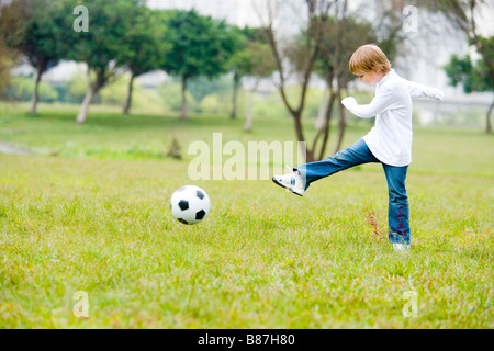 Junge treten Fußball auf dem Rasen-Seitenansicht Stockfoto