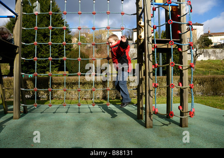 Stock Foto von einem 9-jährigen Jungen springen von einem Klettergerüst auf einem Spielplatz Stockfoto