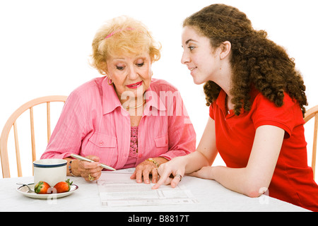 Ältere Frau, die Briefwahl mit Hilfe ihrer Enkelin isoliert auf weiß ausfüllen Stockfoto