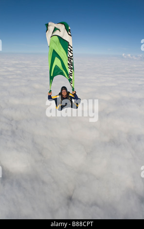 Fallschirmspringer ist hält eine Fahne im freien Fall über eine Wolkenuntergrenze und eine extreme Zeit während dieser Marketing-Promotion-Tauchgang. Stockfoto