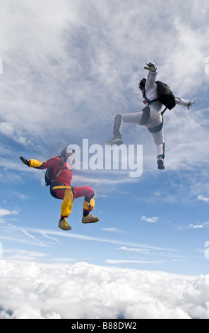 Fallschirmspringer in der Sit-Position über Wolken fallen und fliegen umeinander mit einem lustigen Zeit in den blauen Himmel. Stockfoto