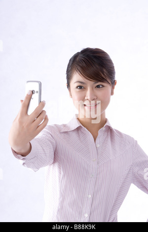 Junge Geschäftsfrau mit Handy um zu fotografieren sich lächelnd Stockfoto