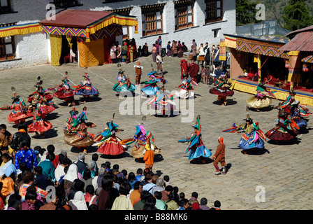 Massen von Menschen in Festival Kleid und tanzende Mönche im Hof des Mongar Dzong während des Festivals Mongar, Stockfoto