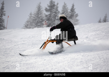 Eine Frau, die auf einem Schnee Scooter bergab eine schneehang Piste. Rauris Österreich Europa Stockfoto
