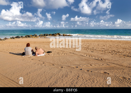 Ein Mann und eine Frau sitzen zusammen am Strand, Blick auf den Ozean. San Juan, Puerto Rico. Stockfoto