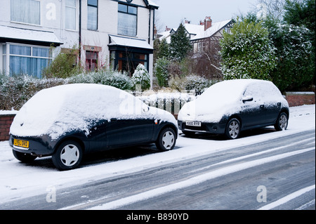 Zwei Autos auf einer Schnee bedeckten und eisigen Straße geparkt. Stockfoto