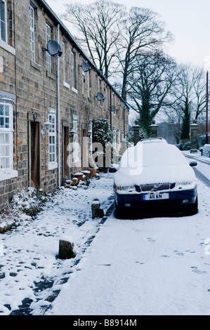 Ein Auto parkte vor seinem Haus auf einer schneebedeckten Straße. Stockfoto