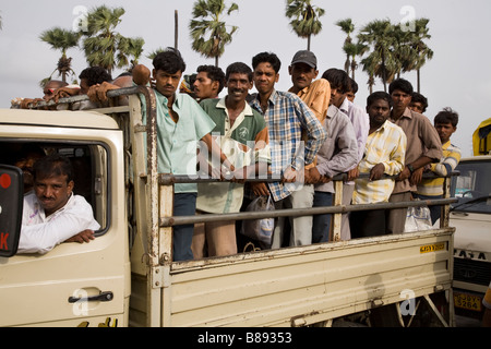 Beiläufige Arbeiter transportierten vom oder zum Arbeiten in einem kleinen Tieflader. Hazira, Surat, Gujarat. Indien. Stockfoto