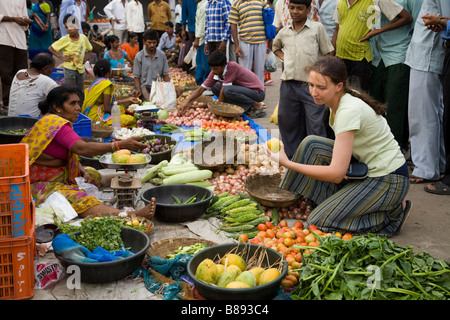 Westliche Touristen wählen und kaufen Obst und Gemüse / kauft Lebensmittel an einem lokalen Marktstand. Hazira, Surat, Gujarat. Indien. Stockfoto