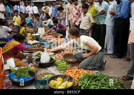 Westliche Frau Touristen kaufen Obst und Gemüse an einer lokalen Marktstand. Hazira, Surat, Gujarat. Indien. Stockfoto