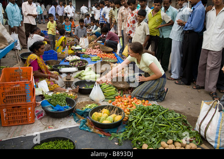 Westliche Frau Touristen kaufen Obst und Gemüse an einer lokalen Marktstand. Hazira, Surat, Gujarat. Indien. Stockfoto