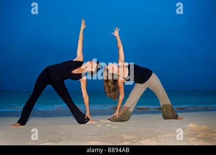 Mutter und Tochter beim Yoga am Strand in Hawaii bei Tagesanbruch Stockfoto
