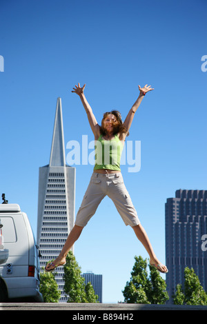 Junge Frau springt in der Innenstadt von San Francisco Stockfoto