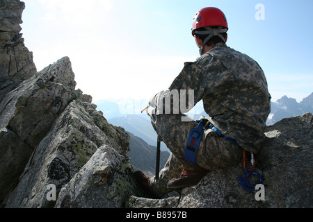 Bergsteiger auf einem Felsen sitzen und mit Blick auf Bergpanorama Stockfoto