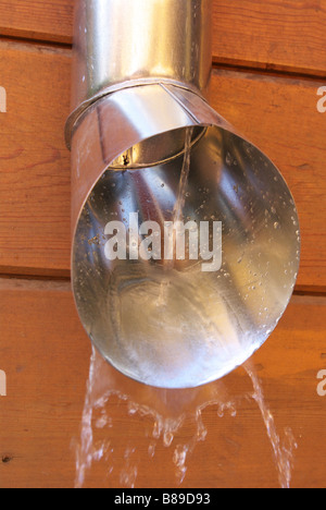 Wasserfluss aus dem Fallrohr installiert auf die Holzwand Stockfoto