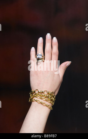 Frau trägt einen großen Diamantring und goldene Armbänder Stockfoto