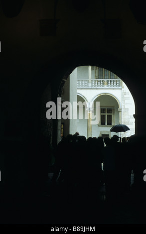 Gruppe von Touristen versteckt vor dem Regen in einem Rundbogen, Schloss Wawel, Krakau, Polen Stockfoto