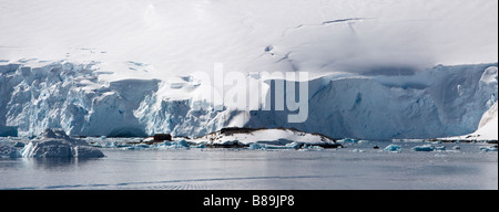 Panoramablick auf riesigen blauen Gletscher Eis und Berge von Schnee oberhalb Port Lockroy Antarktis Forschung winzige Kreuzfahrtpassagiere, die in fernen Base Stockfoto