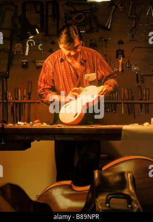 Mann am Arbeitstisch mit Handwerkzeugen im Musikgeschäft Instrument Restaurierung in Avignon Frankreich Stockfoto