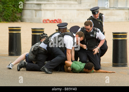 Horizontale Nahaufnahme eines Mannes auf dem Boden Widerstand gegen Verhaftung und wird von zahlreichen Polizei im Zentrum von London mit Handschellen gefesselt. Stockfoto