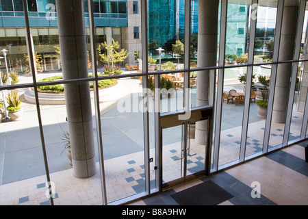 Attraktiven Innenhof Terrasse gesehen durch die Glas-Eingang zu einem modernen Bürogebäude komplexe Stockfoto