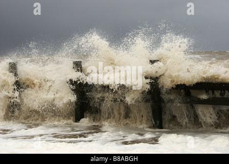 Wellen brechen über eine Buhne (Leiste) bei Happisburgh Beach, Norfolk, England, UK Stockfoto