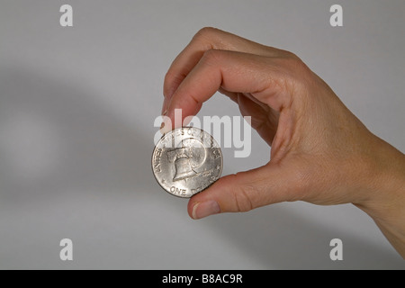 Jemand hält eine US-Silber-Dollar-Münze mit einem Bild von der Liberty Bell zwischen ihren Fingern Stockfoto