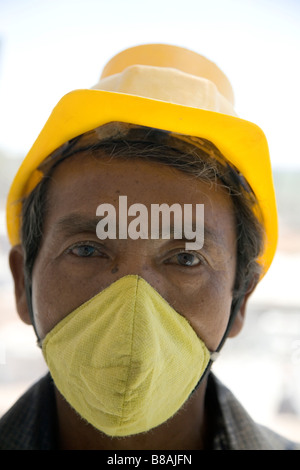 Ein Mann trägt einen Gesichtsschutz und Schutzhelm auf einer Baustelle in Bangalore, Indien. Stockfoto