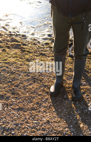 verkürzte Ansicht der männlichen Walker Beine in Wellington Stiefel stehen in der Nähe eine gefrorene Pfütze Stockfoto