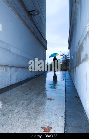 Rückseite des einsamen Frau mit Regenschirm im Durchgang an einem feuchten winterlichen Tag Stockfoto
