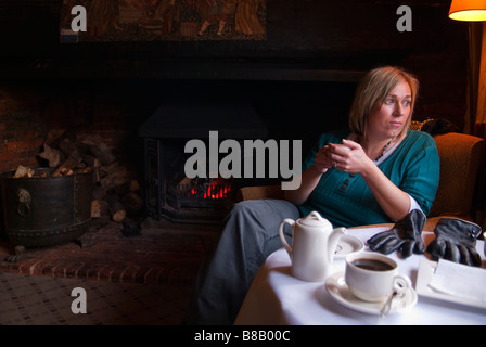 Eine Frau, die Kaffee in Swan Hotel & Restaurant in Lavenham, Suffolk, Uk, Blick aus dem Fenster mit offenem Kamin Stockfoto