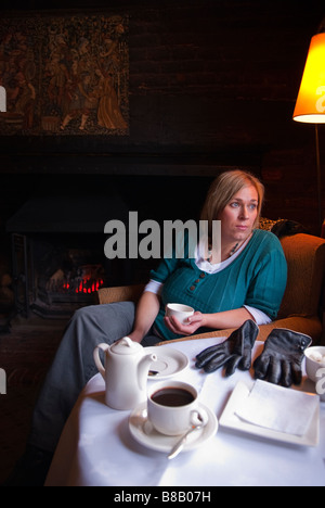 Eine Frau, die Kaffee in Swan Hotel & Restaurant in Lavenham, Suffolk, Uk, Blick aus dem Fenster mit offenem Kamin Stockfoto
