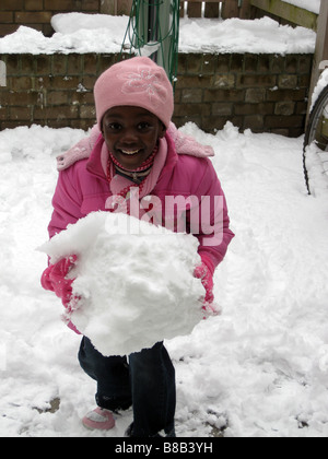 Ein junges Mädchen hält einen Schneeball im Winter in London, England, Vereinigtes Königreich Stockfoto