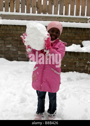 Ein junges Mädchen hält einen Schneeball im Winter in London, England, Vereinigtes Königreich Stockfoto